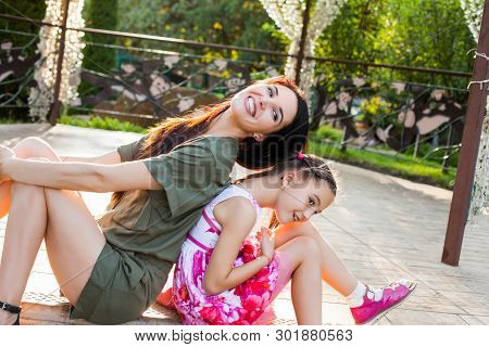 Attractive Mother And Daughter Sitting Back To Back In Arbour, They Laughting, Having Fun And Very H