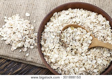 Raw Oatmeal With A Spoon On The Table. Traditional Carbohydrate Breakfast