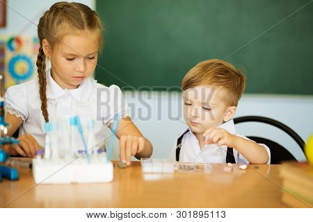 Knowledge Is Always Yours. Cute Little Girl Helping Her Younger Brother At Classroom In School Or Pr