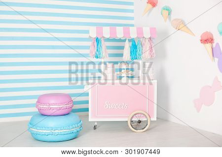 Children Room With Blue Stripe Background. Candy Stall Photo Zone With Big Macaroons, Sweets And Mar