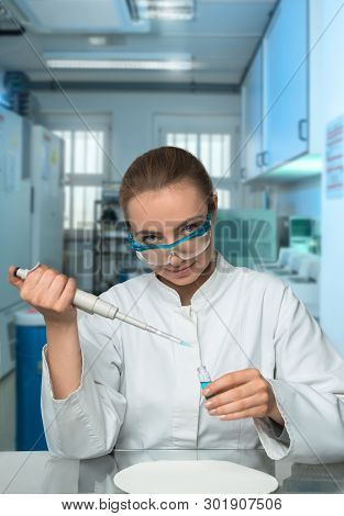 Portrait Of Caucasian Female Scientist Pipetting Sample In Modern Laboratory