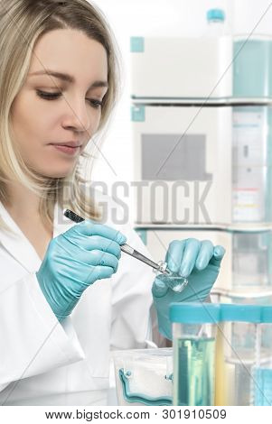 Young Female Tech Or Scientist Picks Up A Piece Of Tissue From Transparent Jar. Shallow Dof, Focus O