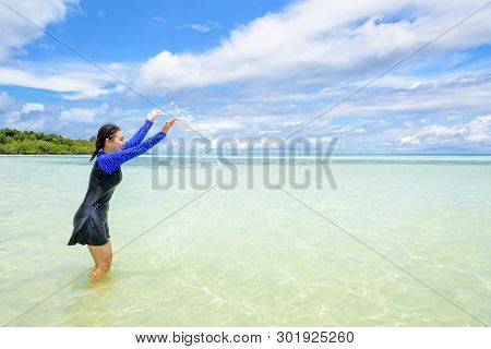 Happy Asian Teen Girl In A Swimsuit Play Splashing Water In The Sea With Fun Under The Blue Sky Of K