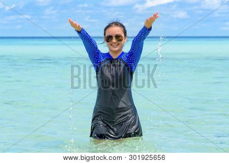 Happy Asian Teen Girl In A Swimsuit Play Splashing Water In The Sea With Fun Under The Blue Sky Of K