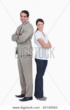Smiling sales team with arms folded standing back to back against a white background
