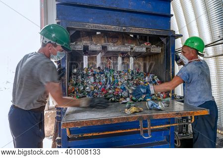 Gubkin, Russia - June 12, 2020: Workers Press Metal Cans. Household Waste Sorting And Recycling Plan