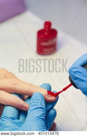 Close-up Of A Woman Applying Red Nail Polish. Womens Beauty Service