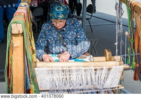 Chelyabinsk, Russia-September 12 2020. Folk art festival. A woman is hand-woven on a hand loom. The fabric is handmade.