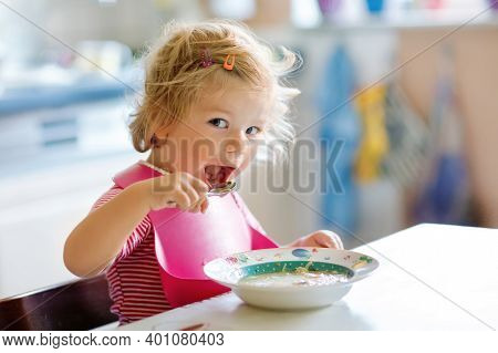 Adorable Baby Girl Eating From Spoon Vegetable Noodle Soup. Food, Child, Feeding And Development Con