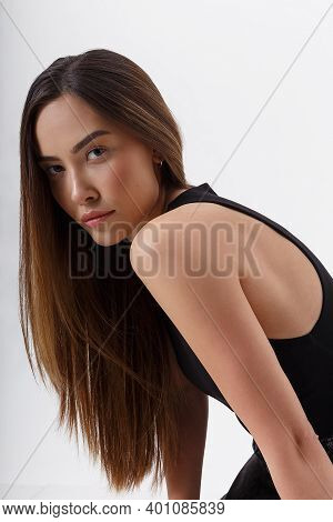 Portrait Of Young Attractive Asian Woman With Long Flowing Hair In Black Clothes, Isolated On White 