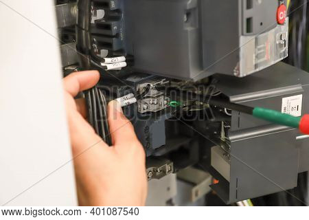The Technician Is Using A Screwdriver Screw The Nut To Secure The Device To The Electric Wire.
