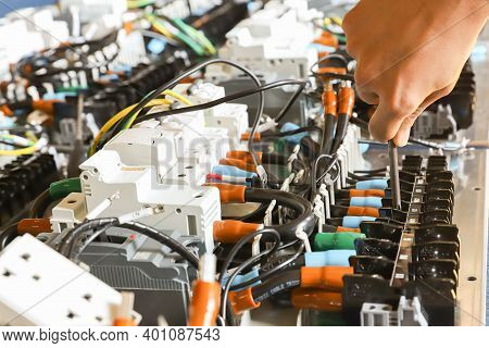 The Technician Is Using A Screwdriver Screw The Nut To Secure The Device To The Electric Wire.