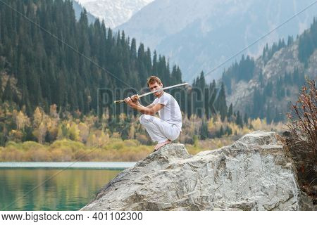 A Barefoot Man Sits On A Stone And Holds A Sword In His Hands. Preparing For The Battle. Man Health 