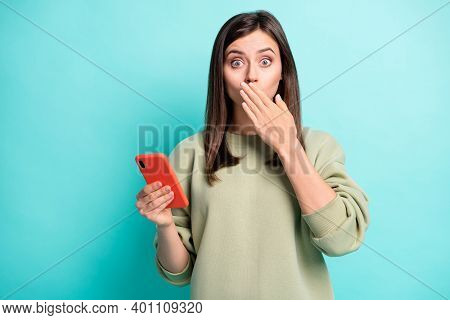 Photo Portrait Of Woman Covering Mouth Lips With One Hand Holding Phone Isolated On Vivid Teal Color
