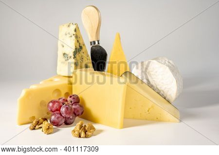 Composition Of Different Types Of Cheese With Walnuts And Grapes On White Background. Blue Cheese Do