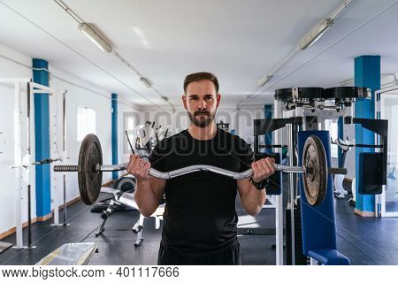Young Man Doing Biceps Curl With Bar. Bar Exercise. Concept Of Health And Wellbeing