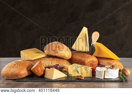 Cheese And Bread. Many Types Of Bread And Cheese On Brown Background. Cheese Platter, Tasting And Pa