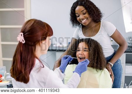 Dental Treatment Without Fear. Female Dentist In Whilte Uniform And Gloves, Examining Teeth Of Littl