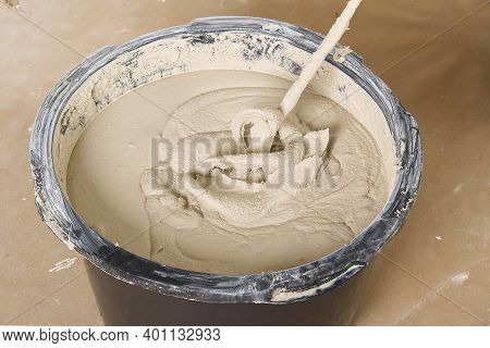 The Master Mixes The Plaster In A Bucket. Flat House Renovation, Master Mixed The Mortar In A Plasti