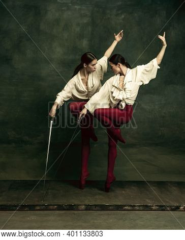 Birds. Two Young Female Ballet Dancers Like Duelists With Swords On Dark Green Background. Caucasian