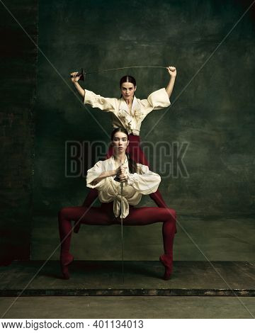 Feelings. Two Young Female Ballet Dancers Like Duelists With Swords On Dark Green Background. Caucas