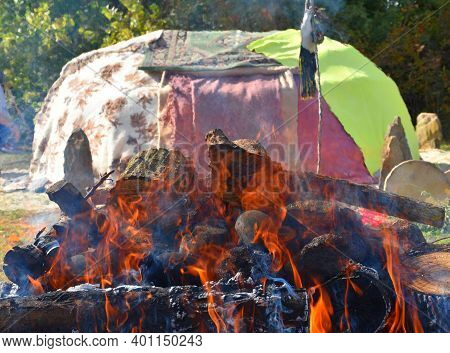 Bonfire With Stones And Inipi Covered With Blankets In The Background.