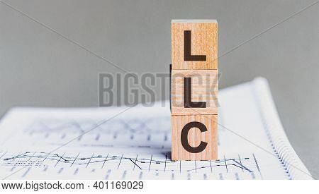 Llc - Limited Liability Company - Acronym On Wooden Cubes On Columns Of Numbers Background. Llc, Acr