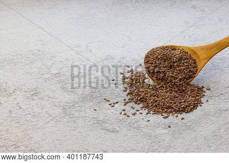 Flax Seeds In A Wooden Spoon On A Gray Concrete Background, A Dietary Product That Reduces Cholester