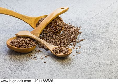 Flax Seeds In A Wooden Spoon On A Concrete Background, A Dietary Product That Reduces Cholesterol, A
