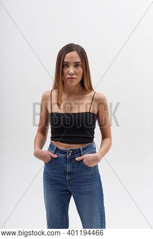 Portrait Of Young Attractive Asian Woman With Long Hair In Black Top, Blue Jeans Isolated On White S