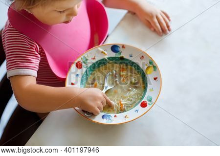 Close-up Baby Girl Eating From Spoon Vegetable Noodle Soup. Food, Child, Feeding And Development Con