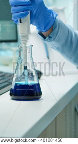 Close Up Of Scientis Testing Liquid Sample Late At Night Using Micropipette For Medical Treatment In
