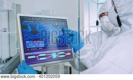 Chemist In Ppe Suit Explainig To Doctor Vaccine Development In Modern Equipped Laboratory Pointing O