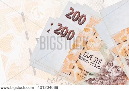 200 Czech Korun Bills Lies In Stack On Background Of Big Semi-transparent Banknote. Abstract Present