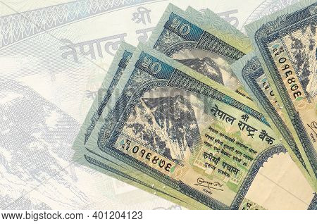 50 Nepalese Rupees Bills Lies In Stack On Background Of Big Semi-transparent Banknote. Abstract Pres