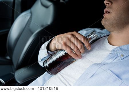 Partial View Of Drunk Man Sleeping With Bottle Of Alcohol On Drivers Seat In Car.