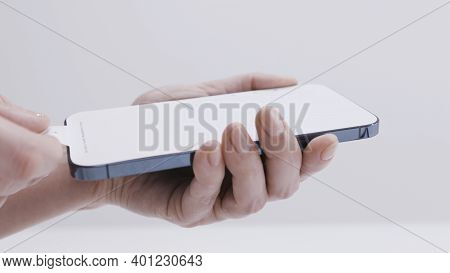 Moscow, Russia-november, 2020: Removing Film From Screen Of New Phone. Action. Close-up Of Man Holdi