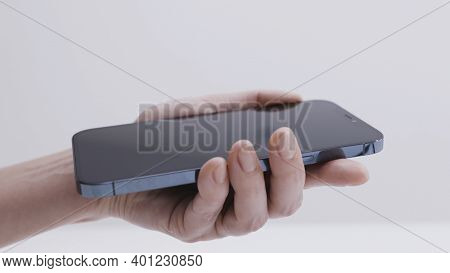 Moscow, Russia-november, 2020: Removing Film From Screen Of New Phone. Action. Close-up Of Man Holdi