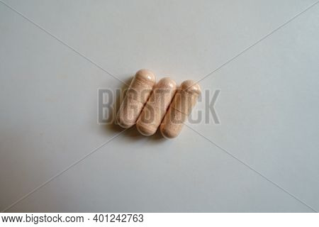 Close View Of Three Pink Capsules Of Probiotic Dietary Supplement