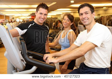 drei Freunde auf Heimtrainer in einer Turnhalle