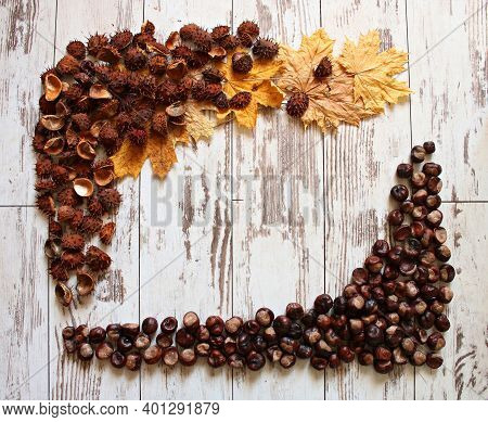 An Impromptu Frame Made Of Chestnut Fruits And Dry Yellow Leaves On Old Boards