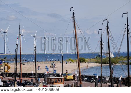 Urk, The Netherlands - June 15 2020 Windmills On The Coast With Trees, Boat Masts And People. Wind P