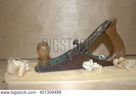 An Old Hand Jack Plane On A Wooden Table, Next To A Wooden Sawdust In The Workshop. Carpenter Tools.
