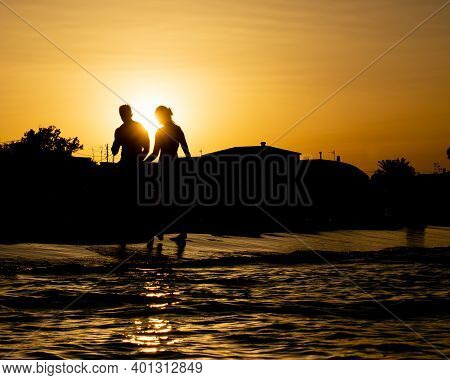 Beautiful Backlighting Sunset With A Couple Walking On The Beach In Denia, Alicante, Spain