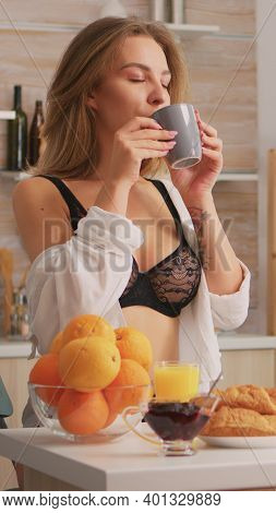 Attractive Woman In Black Ligerie Relaxing With Coffee During Breakfast Sitting In Kitchen And Smili