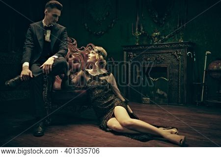 Fashion clothes, make-up and hair in luxurious retro style. Handsome man and beautiful young woman in the style of the 1920s in rich vintage apartments. 
