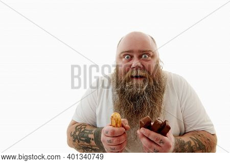 An Overweigh Man Greedily Holding Chocolate Bars And Cake And Looking At Camera. Concept Of An Unhea