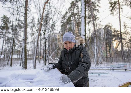 Cheerful Caucasian Boy In Winter Clothes Dressed A Snowball Maker On His Head And Smiling In A Winte