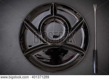 Plate For A Chinese Fondue With A Fondue Fork On The Dark Background, Top View