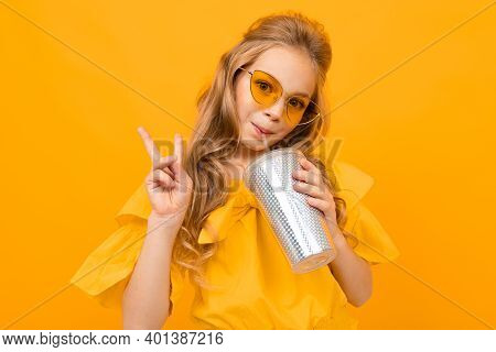 Portrait Of Young Caucaian Girl With Long Fair Hair In Yellow Glasses Drinks A Juice And Smiles